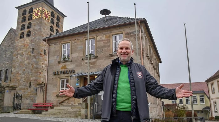 Bürgermeister und Wärmeplaner steht vor dem Rathaus und der Kirche